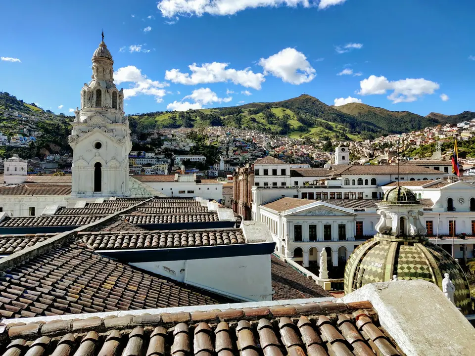 Tejados y campanario del centro histórico de Quito con montañas al fondo